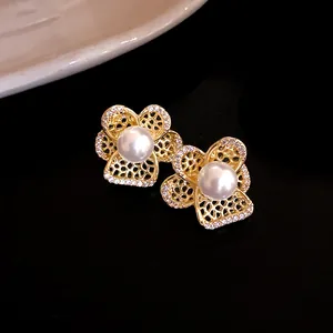 Vista detallada de pendientes de flor calada con perla central y circonitas brillantes