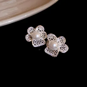 Detalle de pendientes de botón de flor calada con elegantes centros de perlas blancas