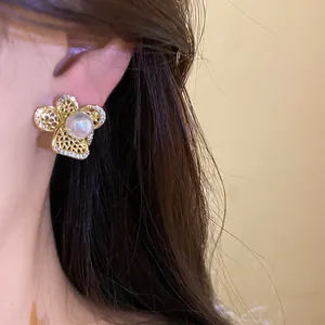 Primer plano de un elegante pendiente de flor hueca con detalles de perla y circón.