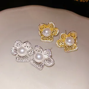 Detalle de pendientes de flores caladas en oro y plata con perlas y circonitas engastadas.
