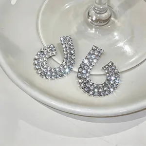Close-up detail of silver geometric earrings with shimmering rhinestone embellishments.