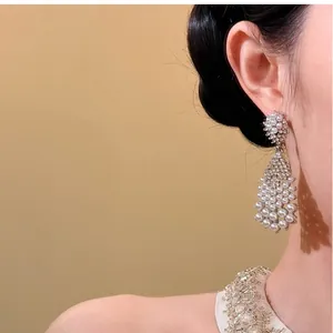 Close-up view of elegant teardrop-shaped pearl and zircon dangle earring on model ear