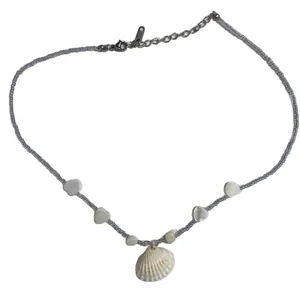 Summer beaded necklace with seashell pendant and heart shell accents on white background.