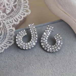 Macro view of silver-toned geometric stud earrings with sparkling crystals on grey base.