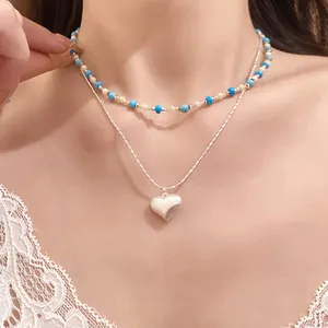 Detail view of a dainty layered heart pendant necklace with blue beaded choker