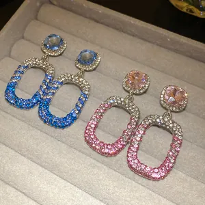 Dettaglio di orecchini pendenti quadrati con strass colorati e ago in argento