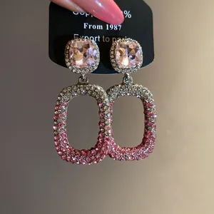 Dettaglio degli orecchini pendenti a goccia scavati con strass rosa sfumati di lusso