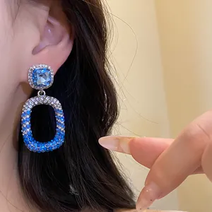 Dettaglio di orecchini in argento con pendente in cristallo blu e pavé di diamanti.