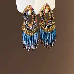Close-up of bohemian water-drop earrings with colorful rhinestones and blue tassels.