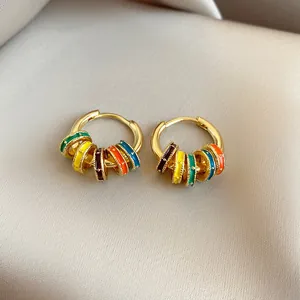 Close-up of gold-plated hoop earrings with vibrant colorful enamel rings