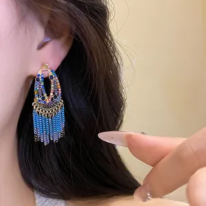 Bohemian blue tassel earrings with vibrant colorful gemstones shown on an ear model