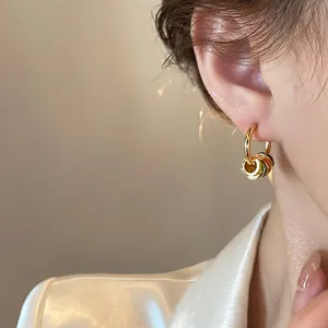 Detail view of gold-plated hoop earrings with vibrant colorful enamel charms worn on ear