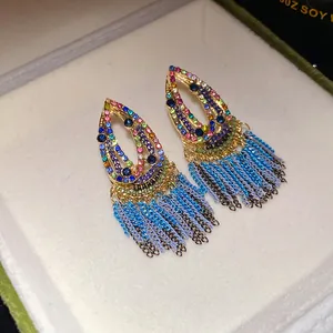 Detailed view of bohemian teardrop earrings with colorful stones and blue chain tassels