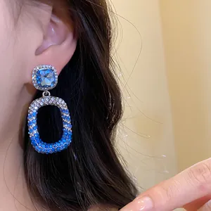 Primo piano di eleganti orecchini a pendente con cristalli blu sfumati e argento.