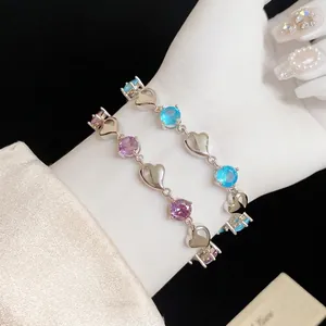 Elegant heart-shaped silver bracelet featuring blue and purple cubic zirconia stones.
