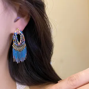 Macro view of bohemian waterdrop earrings with vibrant gemstones and blue gradient tassels