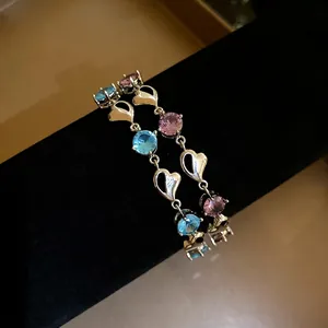 Minimalist fashion heart bracelet with blue and pink zircon stones on black stand