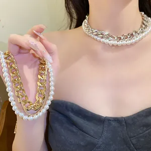 Close-up detail of layered necklace with chunky gold chain and white pearl beads