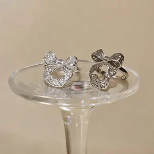 Close-up of elegant hollow bow-shaped open rings with intricate textured metal detailing