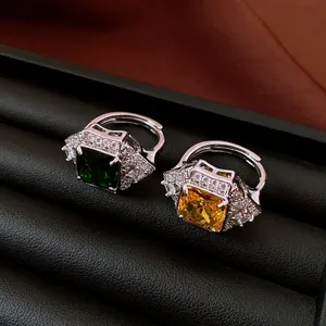 Close-up of vintage square emerald and yellow zircon rings displayed on dark leather box