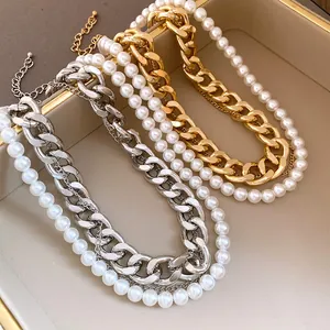 Detail of layered necklace featuring chunky gold and silver chains with white pearls
