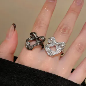 Detailed macro shot of silver and black hollow-out mesh bow-knot open rings worn on a hand