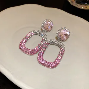 Dettaglio di orecchini pendenti rettangolari con strass pavé rosa su ago in argento.
