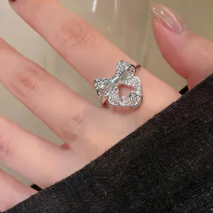 Detailed close-up view of an elegant silver hollow-out bow open ring worn on a finger
