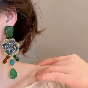 Detailed view of vintage green rose dangle earrings with colorful resin beads on a model.