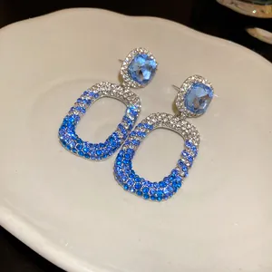 Vista macro di eleganti orecchini pendenti in argento con cristalli sfumati blu e trasparenti.