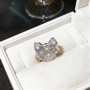 Detailed view of elegant silver bow-knot ring with hollow filigree design in box