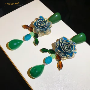 Close-up of vintage artistic green rose drop earrings with elegant gold details