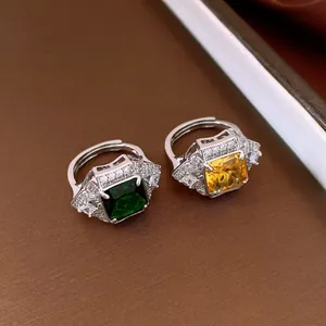 Close-up of vintage square emerald and yellow zircon open rings on brown texture