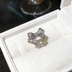 Close-up of a silver bow-shaped open ring with intricate hollow design in a gift box