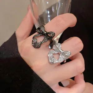 Detail of elegant hollow bow rings with pavé crystals on hand worn by model.