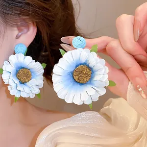 Detail van handgemaakte stoffen madeliefje oorbellen met blauw-witte kleurverloop