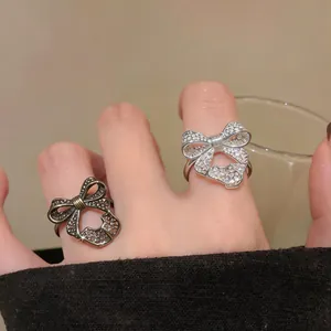 Detailed macro shot of elegant silver and bronze bow-shaped open rings on fingers