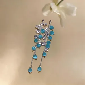 Detailed macro view of blue cat-eye stone tassel earrings with silver finish and zircons.