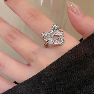 Close-up of a silver hollow mesh bow ring on a finger with adjustable open band