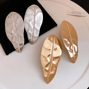 Large leaf-shaped metal earrings with a bright gold and silver finish