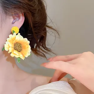 Detail van handgemaakte gele stoffen zonnebloem oorbellen gedragen door een model