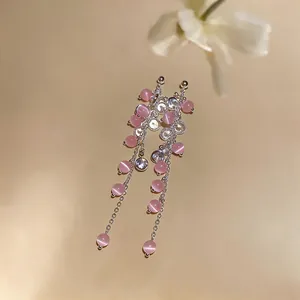 Detailed close-up of silver tassel earrings with pink cat-eye beads and clear zircon stones.