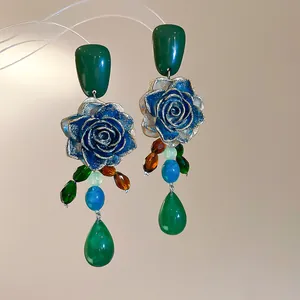 Detailed macro view of vintage blue gold rose earrings with green teardrop beads