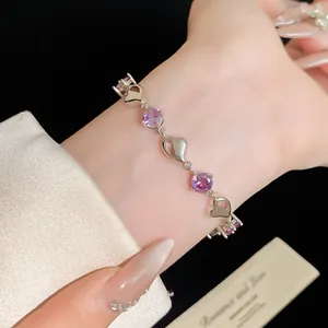 Close-up of elegant silver bracelet with purple zircons and heart shapes on wrist.