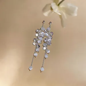 Close-up of silver-tone tassel earrings featuring zircon and white cat eye stone beads.