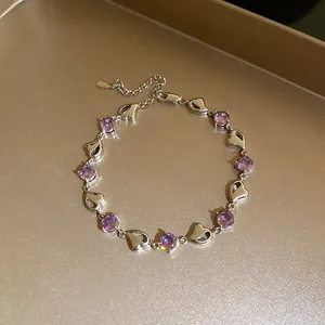 Detailed view of a silver bracelet with purple zircons and heart-shaped charms.