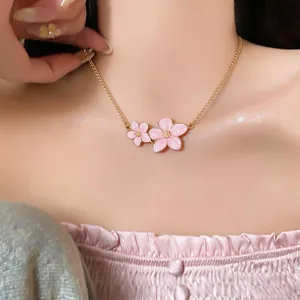 Detailed view of an elegant pink enamel cherry blossom necklace on a model's neck
