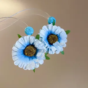 Detail van handgemaakte blauwe stoffen madeliefje oorbellen met getextureerd hartje