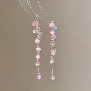 Close-up view of elegant pink cat's eye stone tassel earrings with dangling silver chains