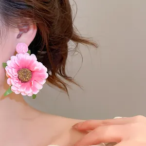 Detailopname van een grote handgemaakte roze stoffen madeliefje oorbel gedragen aan oor